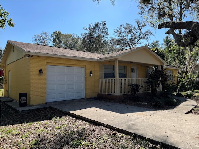 single story home featuring a porch, concrete driveway, brick siding, and a garage