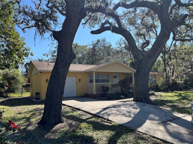 single story home with an attached garage, fence, a porch, and a front yard