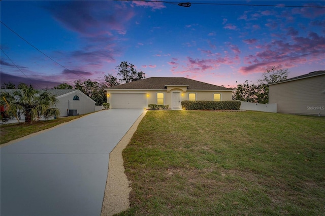 ranch-style house featuring stucco siding, concrete driveway, a lawn, fence, and a garage