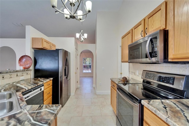 kitchen with arched walkways, a notable chandelier, a sink, appliances with stainless steel finishes, and tasteful backsplash