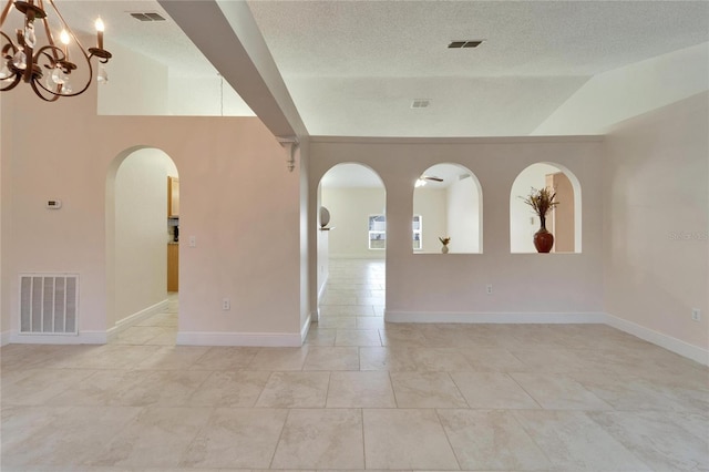 spare room featuring lofted ceiling, visible vents, and arched walkways