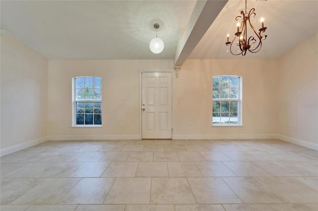 unfurnished room with baseboards, a chandelier, a textured ceiling, and light tile patterned flooring