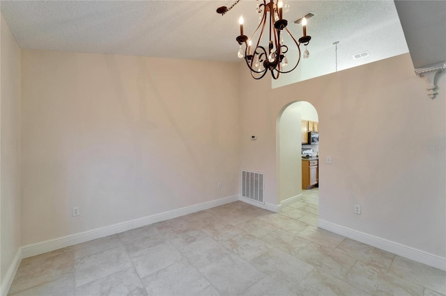 spare room featuring arched walkways, visible vents, a notable chandelier, and baseboards