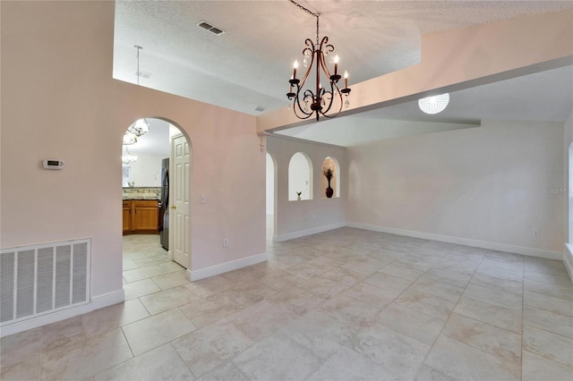 unfurnished room featuring baseboards, visible vents, arched walkways, and a textured ceiling