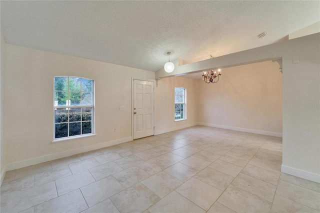 empty room with visible vents, a textured ceiling, baseboards, and an inviting chandelier