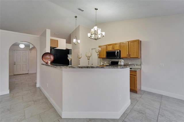 kitchen with arched walkways, stainless steel microwave, brown cabinets, vaulted ceiling, and fridge