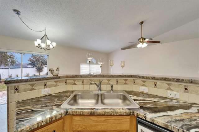 kitchen with dark countertops, vaulted ceiling, a sink, and a textured ceiling