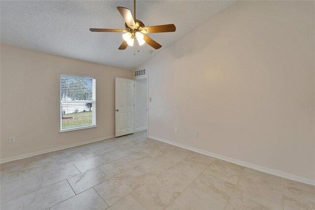 empty room featuring ceiling fan, a textured ceiling, visible vents, baseboards, and vaulted ceiling