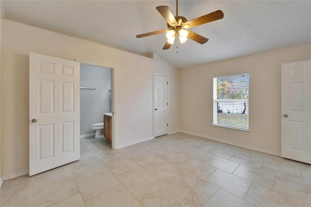 unfurnished bedroom featuring connected bathroom, vaulted ceiling, a textured ceiling, and baseboards