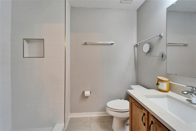 bathroom featuring toilet, tile patterned floors, a tile shower, a textured ceiling, and vanity