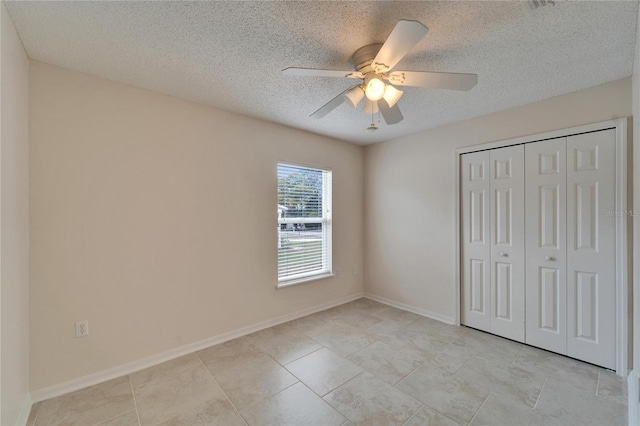 unfurnished bedroom with light tile patterned floors, baseboards, a ceiling fan, a textured ceiling, and a closet