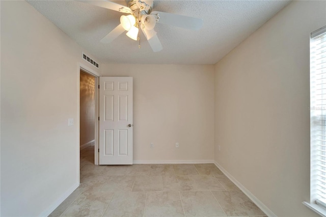 spare room with baseboards, visible vents, and a textured ceiling