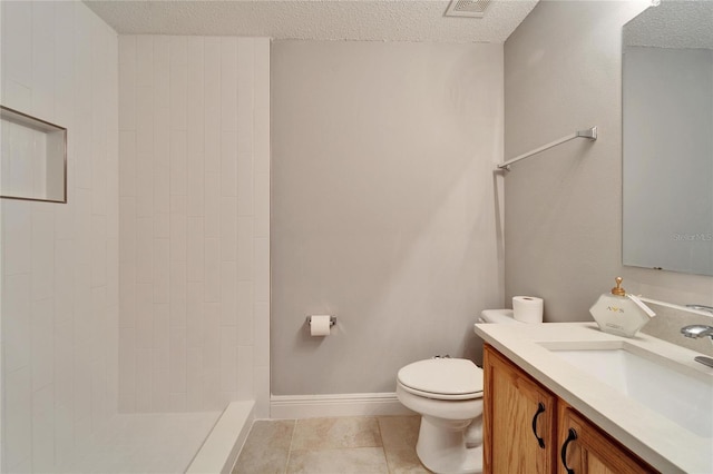 bathroom featuring toilet, a textured ceiling, tiled shower, and vanity