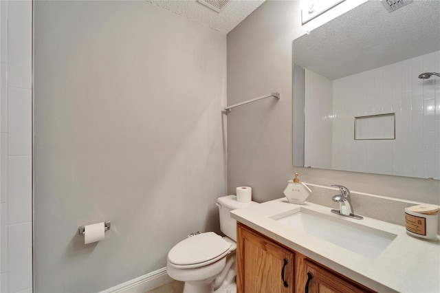 bathroom with baseboards, visible vents, toilet, a textured ceiling, and vanity