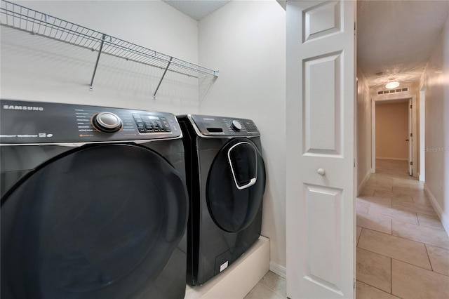 washroom featuring visible vents, light tile patterned flooring, washer and dryer, laundry area, and baseboards