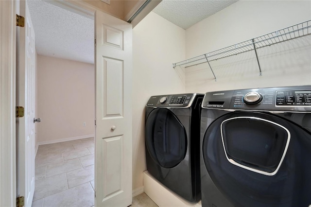 clothes washing area with a textured ceiling, laundry area, washing machine and dryer, and baseboards