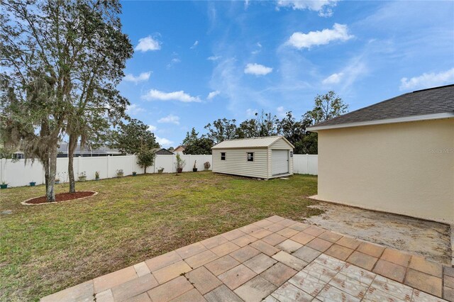 view of yard featuring an outbuilding, a fenced backyard, and a patio