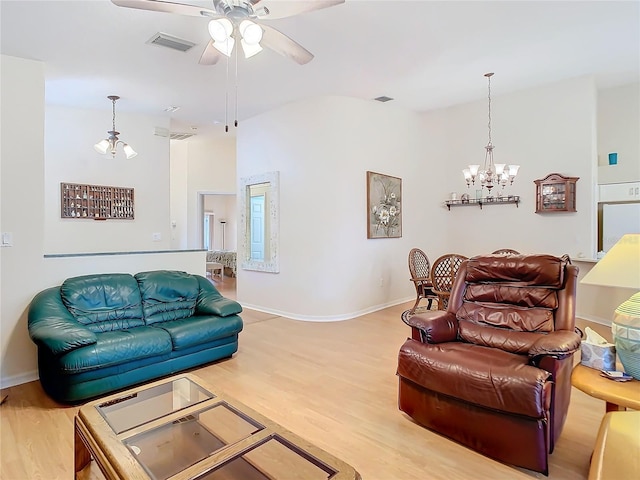 living area with visible vents, ceiling fan with notable chandelier, baseboards, and wood finished floors