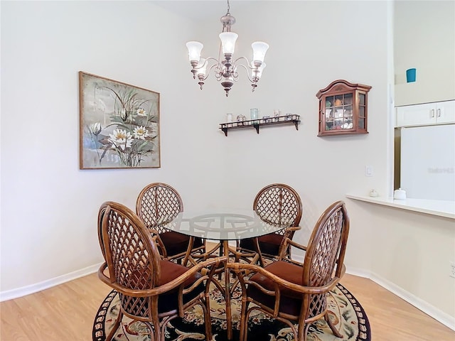 dining space featuring light wood-type flooring, baseboards, and a notable chandelier