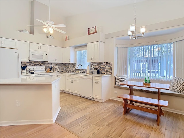 kitchen featuring light countertops, light wood-style flooring, ceiling fan with notable chandelier, white appliances, and white cabinetry