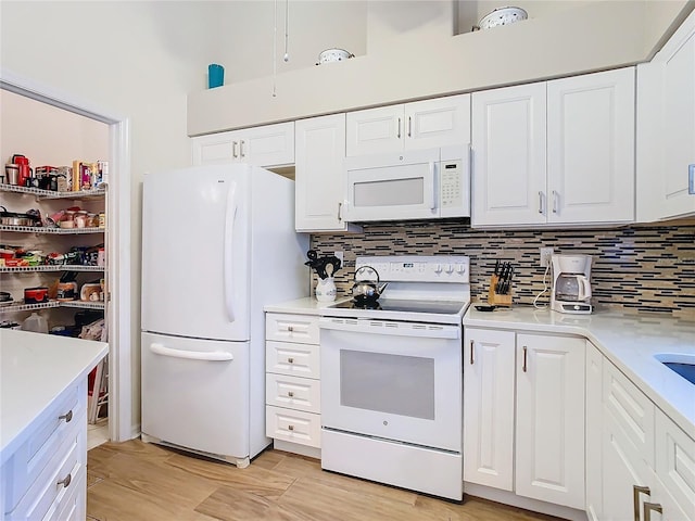 kitchen with white appliances, tasteful backsplash, and white cabinetry