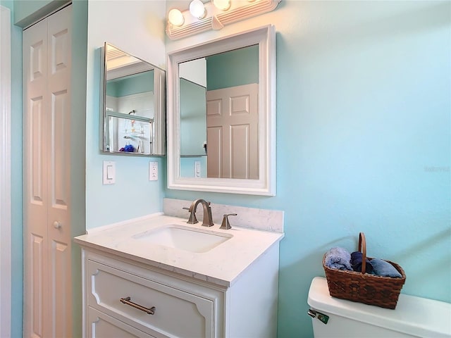 bathroom featuring a closet, toilet, and vanity