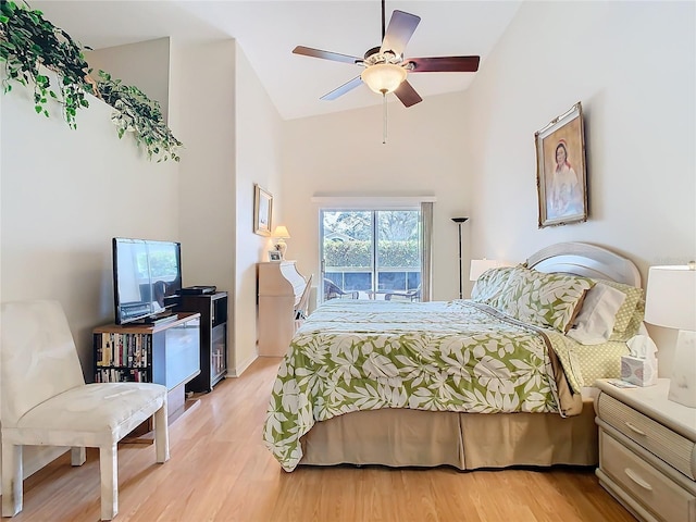 bedroom with access to exterior, a ceiling fan, light wood-type flooring, and high vaulted ceiling