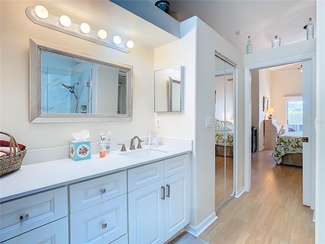 bathroom featuring walk in shower, vanity, wood finished floors, ensuite bath, and a ceiling fan