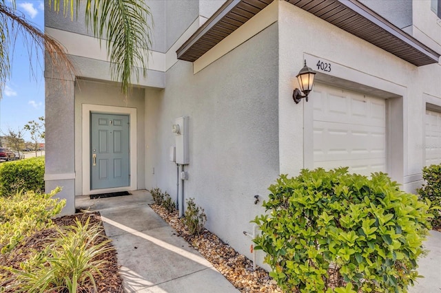 property entrance with a garage and stucco siding