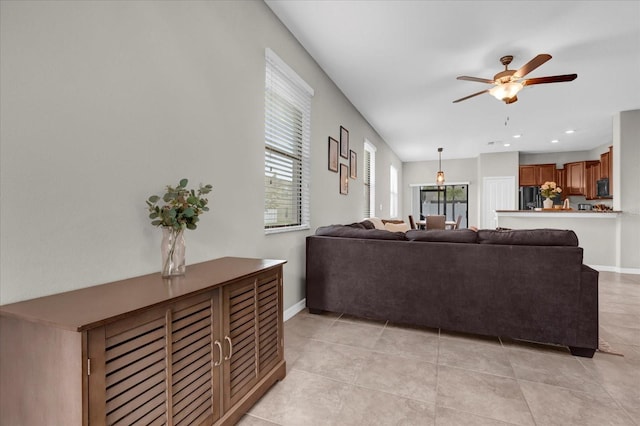 living area with ceiling fan, baseboards, and light tile patterned floors