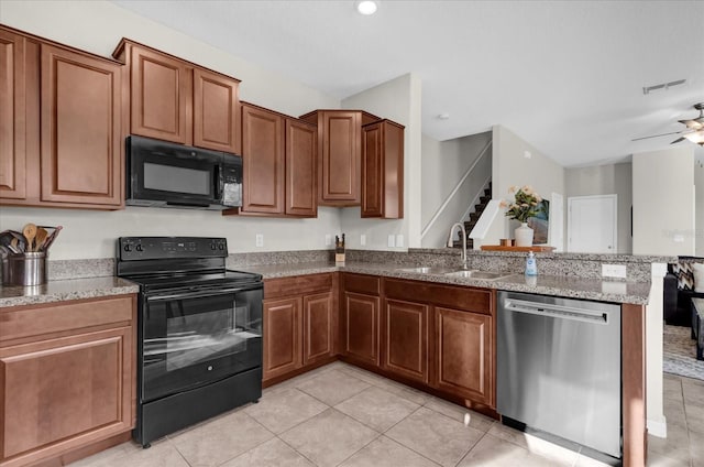 kitchen featuring light stone counters, a sink, black appliances, brown cabinets, and a peninsula