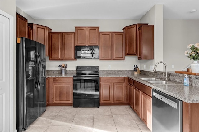 kitchen with a sink, brown cabinetry, black appliances, light tile patterned floors, and a peninsula