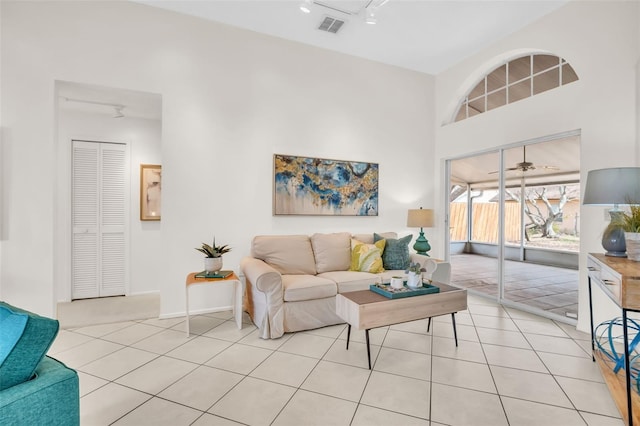 living area with visible vents, a towering ceiling, track lighting, and light tile patterned flooring