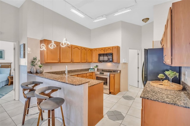 kitchen with dark stone countertops, black appliances, a high ceiling, and a peninsula