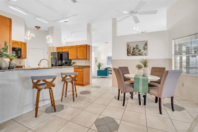 dining space with a towering ceiling, light tile patterned floors, ceiling fan, and rail lighting