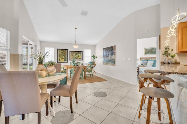 dining area with light tile patterned floors, visible vents, high vaulted ceiling, and baseboards