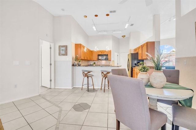 dining area with light tile patterned floors, a high ceiling, visible vents, and baseboards