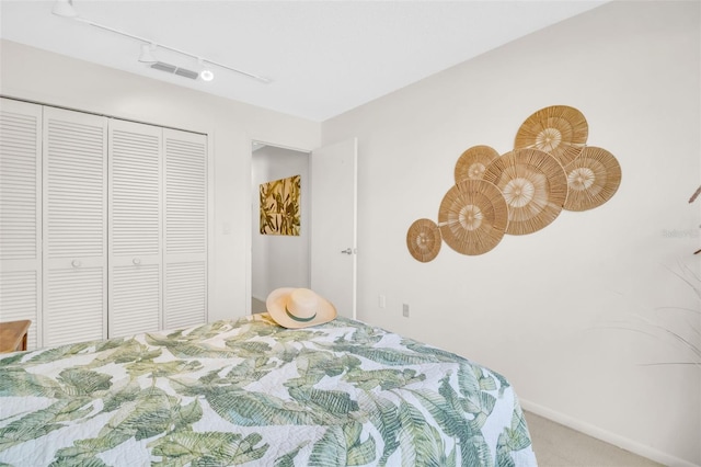 bedroom with track lighting, a closet, visible vents, and carpet flooring