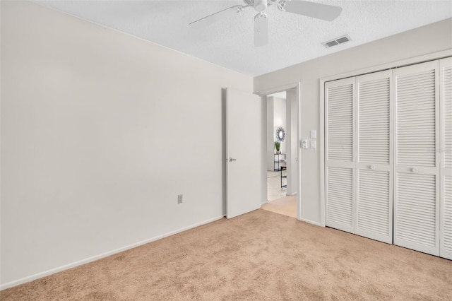 unfurnished bedroom featuring carpet floors, a closet, visible vents, ceiling fan, and a textured ceiling