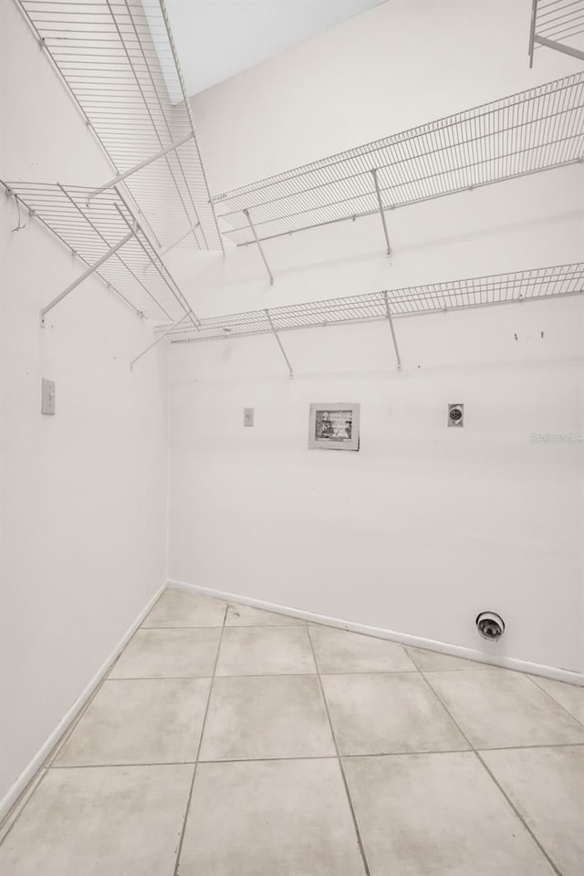 laundry room featuring laundry area, hookup for an electric dryer, baseboards, and light tile patterned floors