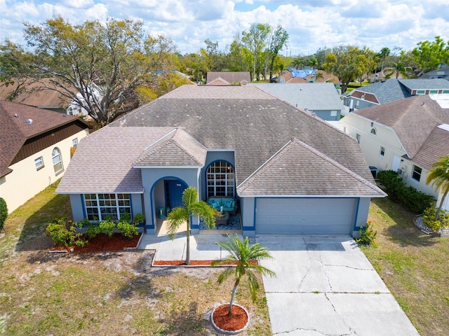 view of front of house with an attached garage, driveway, roof with shingles, stucco siding, and a front yard