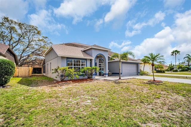 view of front of home with a garage, fence, driveway, stucco siding, and a front yard