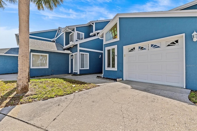 view of front facade featuring a garage, driveway, and stucco siding