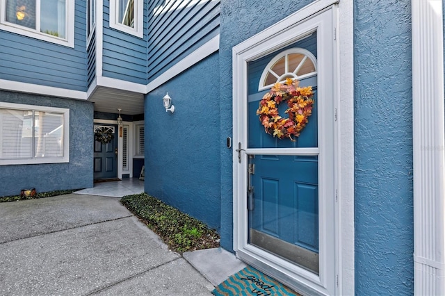 doorway to property featuring stucco siding