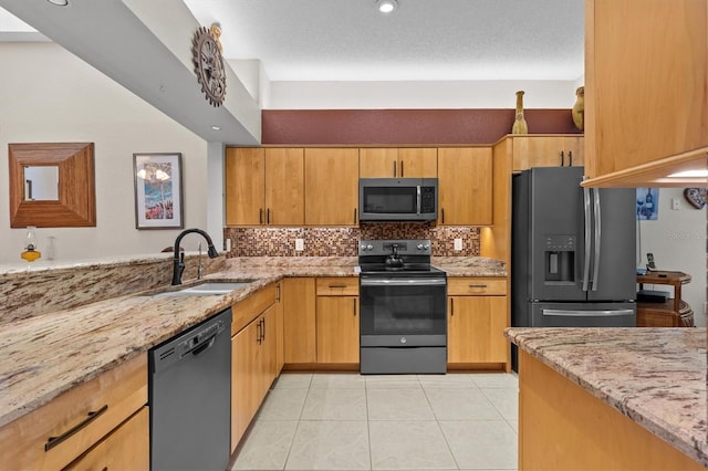 kitchen with stainless steel appliances, a sink, light stone counters, and light tile patterned floors