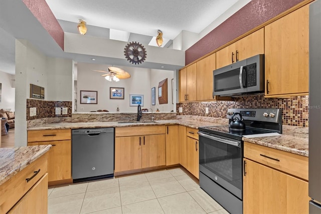 kitchen with electric range, dishwasher, stainless steel microwave, light stone counters, and a sink