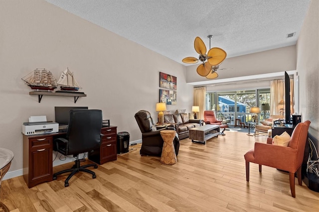 office with visible vents, light wood-style flooring, baseboards, and a textured ceiling