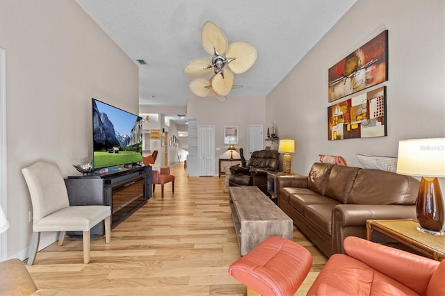 living room featuring light wood-style floors, visible vents, baseboards, and a ceiling fan