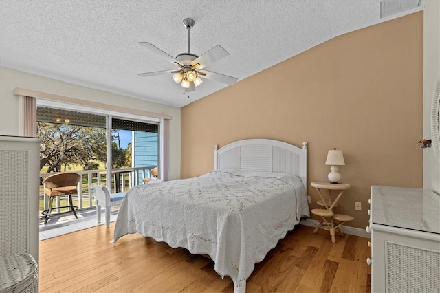 bedroom featuring access to exterior, visible vents, a textured ceiling, and wood finished floors