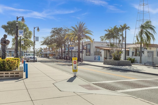 view of road with street lights, curbs, traffic signs, and sidewalks